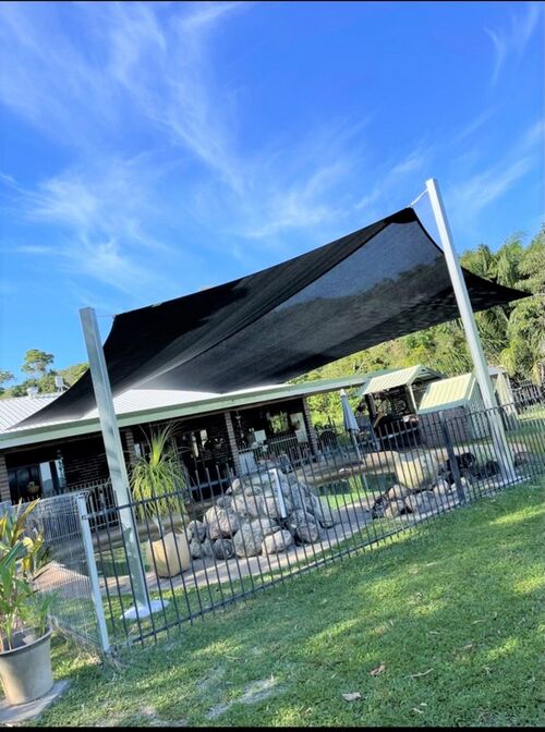 The ultimate in solar protection, a charcoal shade sail over pool in back yard.